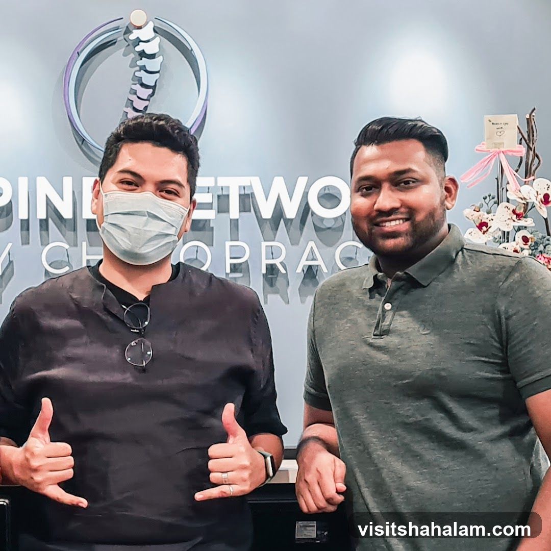Two men in front of a chiropractic clinic sign