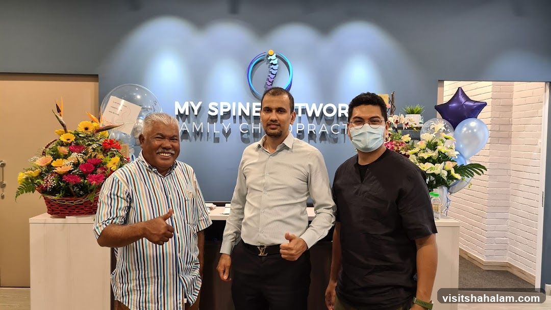 Three men posing in front of a chiropractic clinic sign