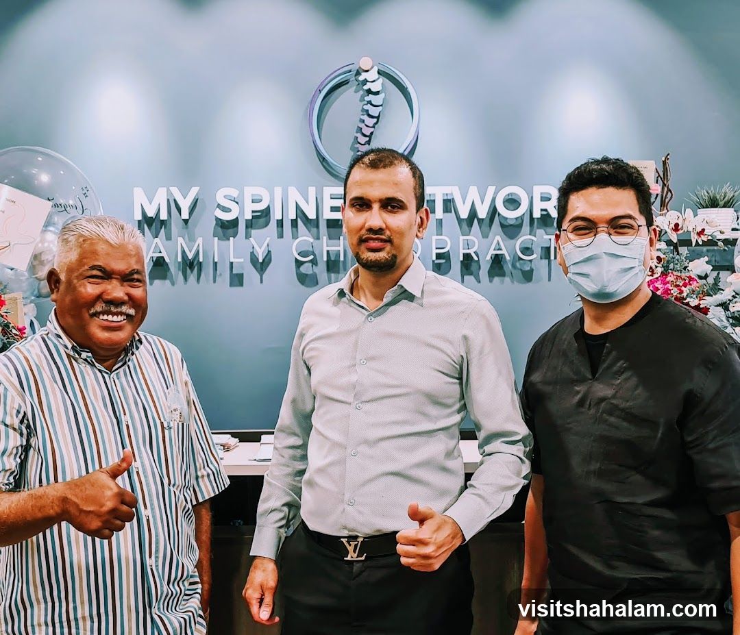 Three men posing in front of a clinic sign