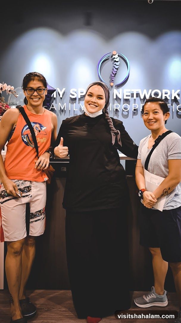 Three people posing in front of a sign