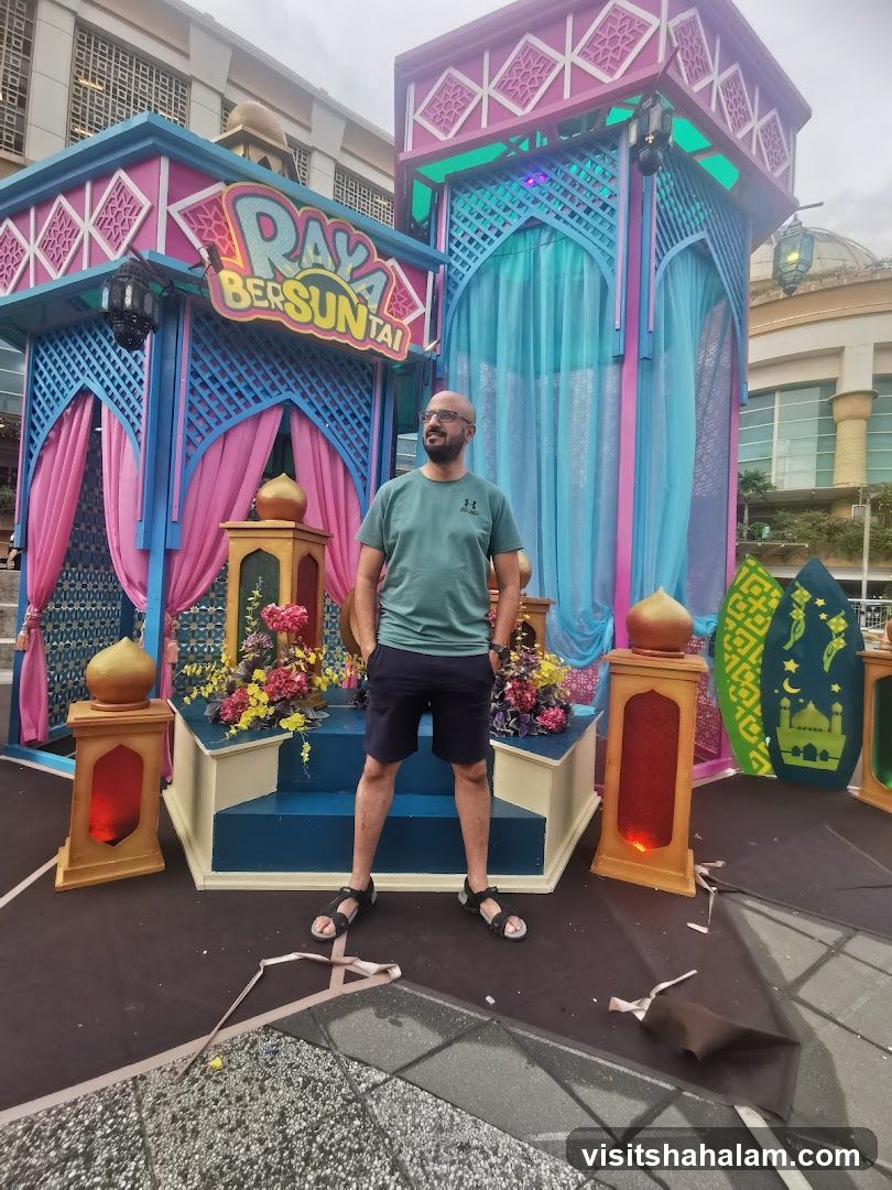Man Poses in Front of Raya Decorations