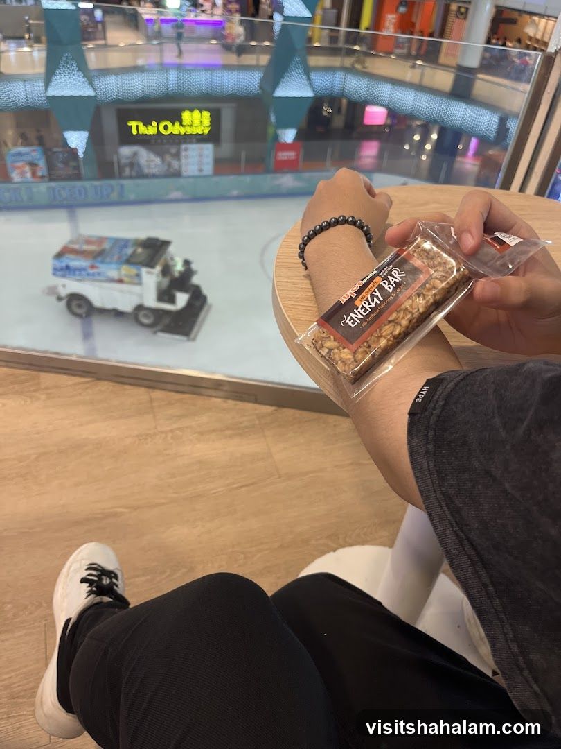 Person holding an energy bar with an ice rink in the background