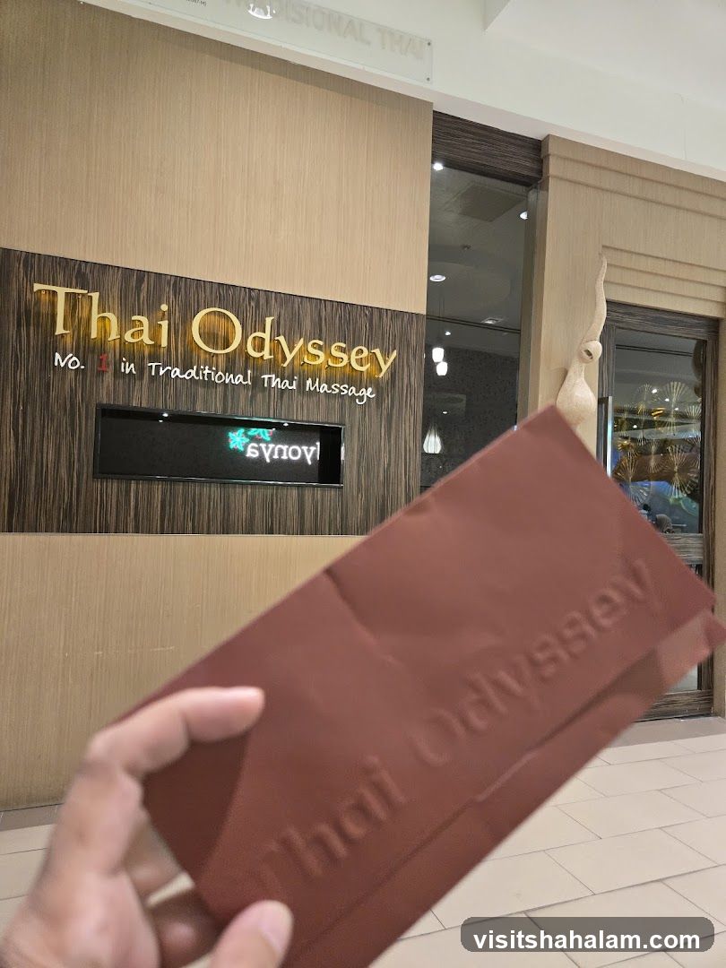 The exterior of a Thai massage parlor with a prominent sign that reads "Thai Odyssey No. 1 in Traditional Thai Massage." A hand holds a brown embossed card with the same business name.