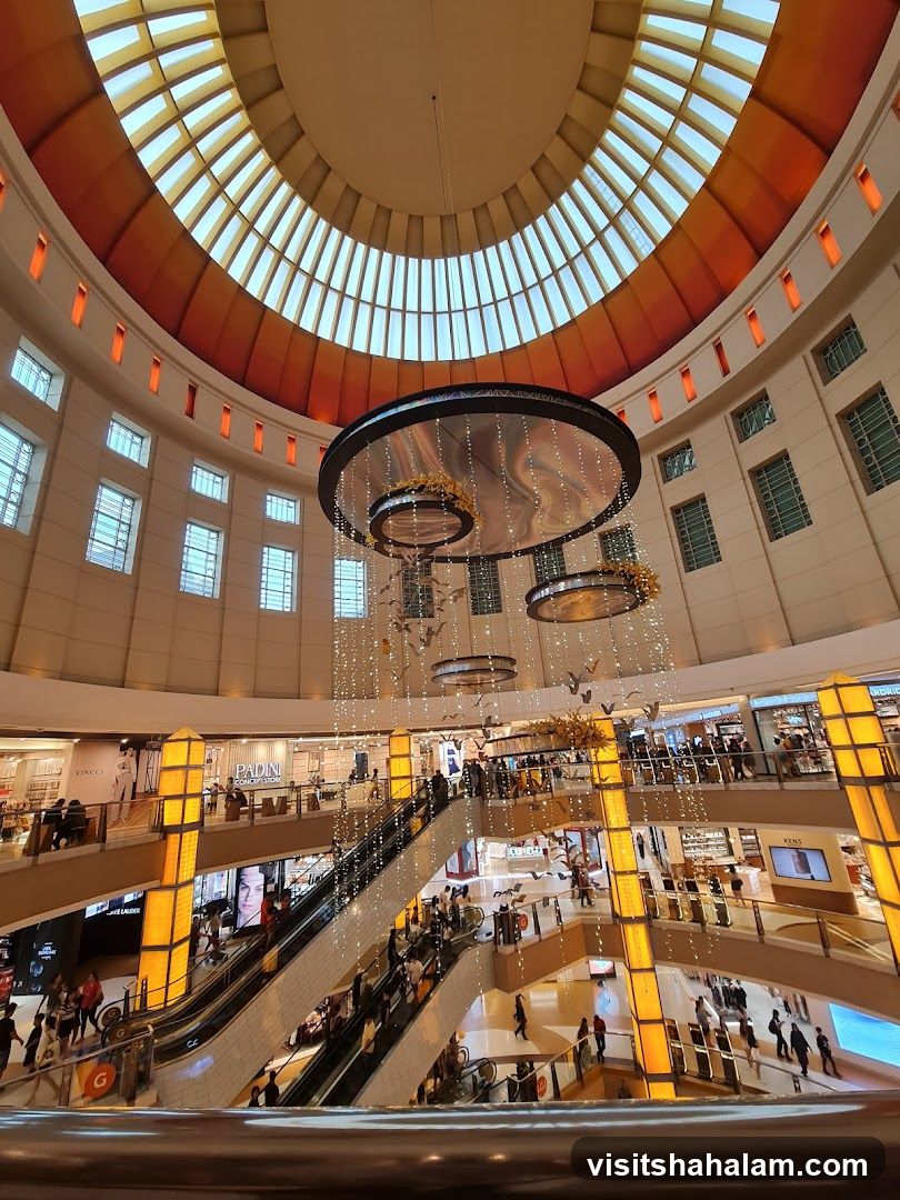 Interior of a multi-level shopping mall with escalators and a large domed ceiling.