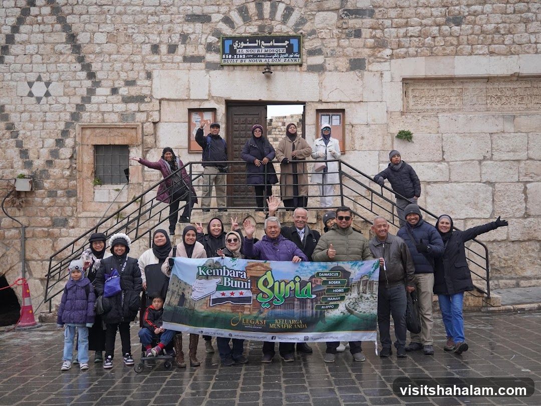 Group posing with a banner in front of a mosque