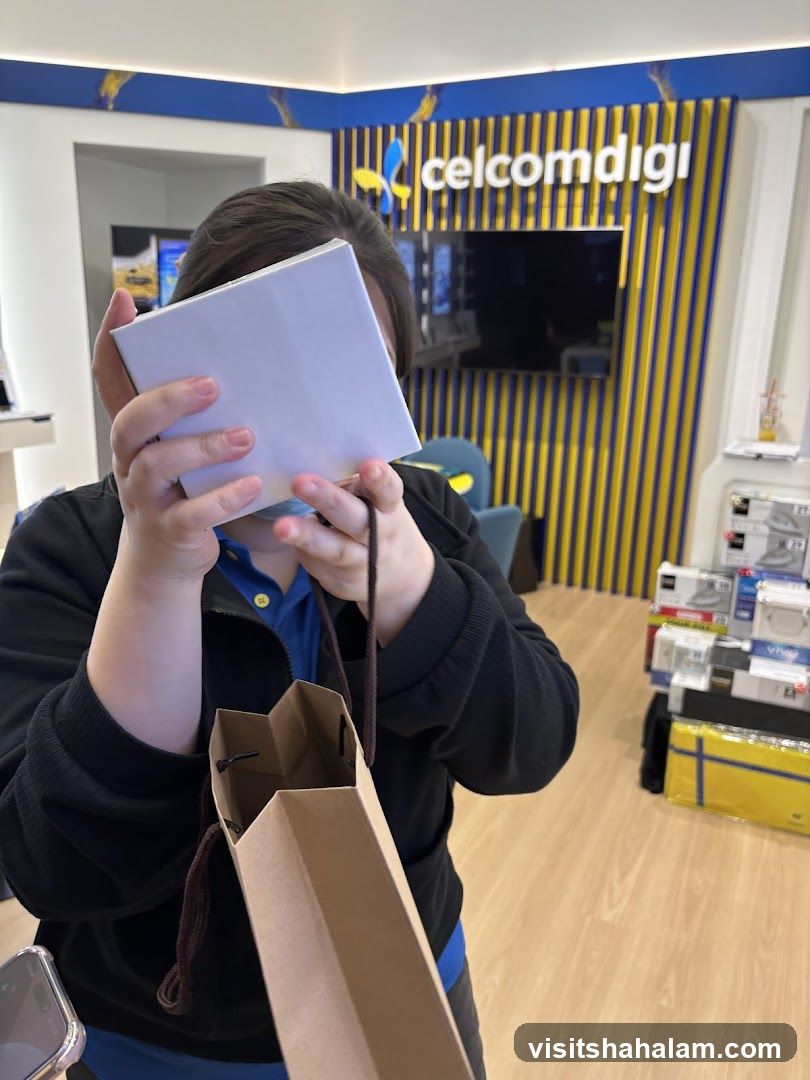 Person holding a box and shopping bag in front of a CelcomDigi store