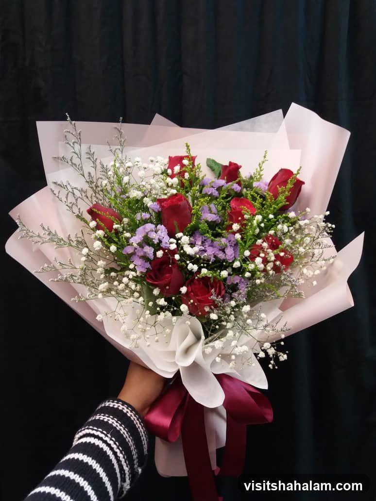 Hand holding a bouquet of red roses
