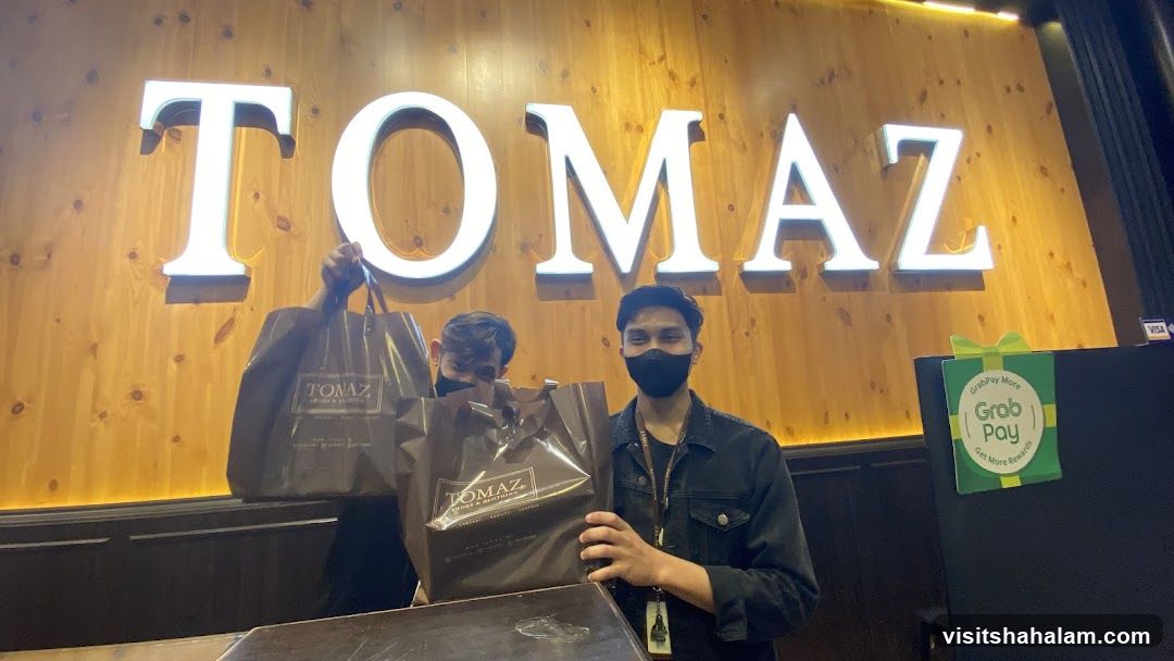Two men holding shopping bags in front of a store sign
