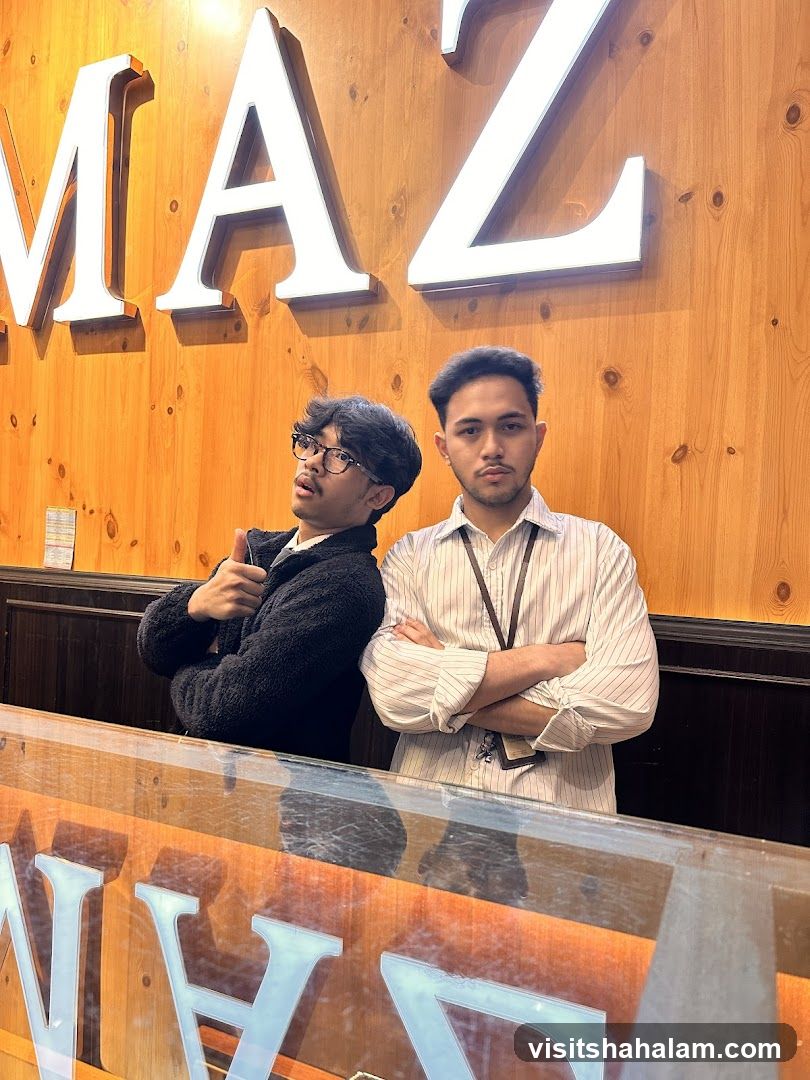 Two men posing in front of a wooden wall with large illuminated letters