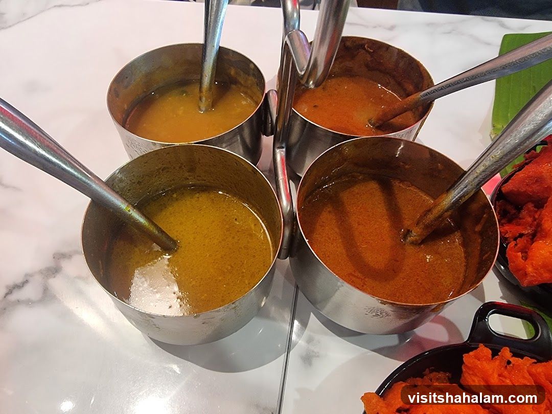 Four bowls of curry with spoons
