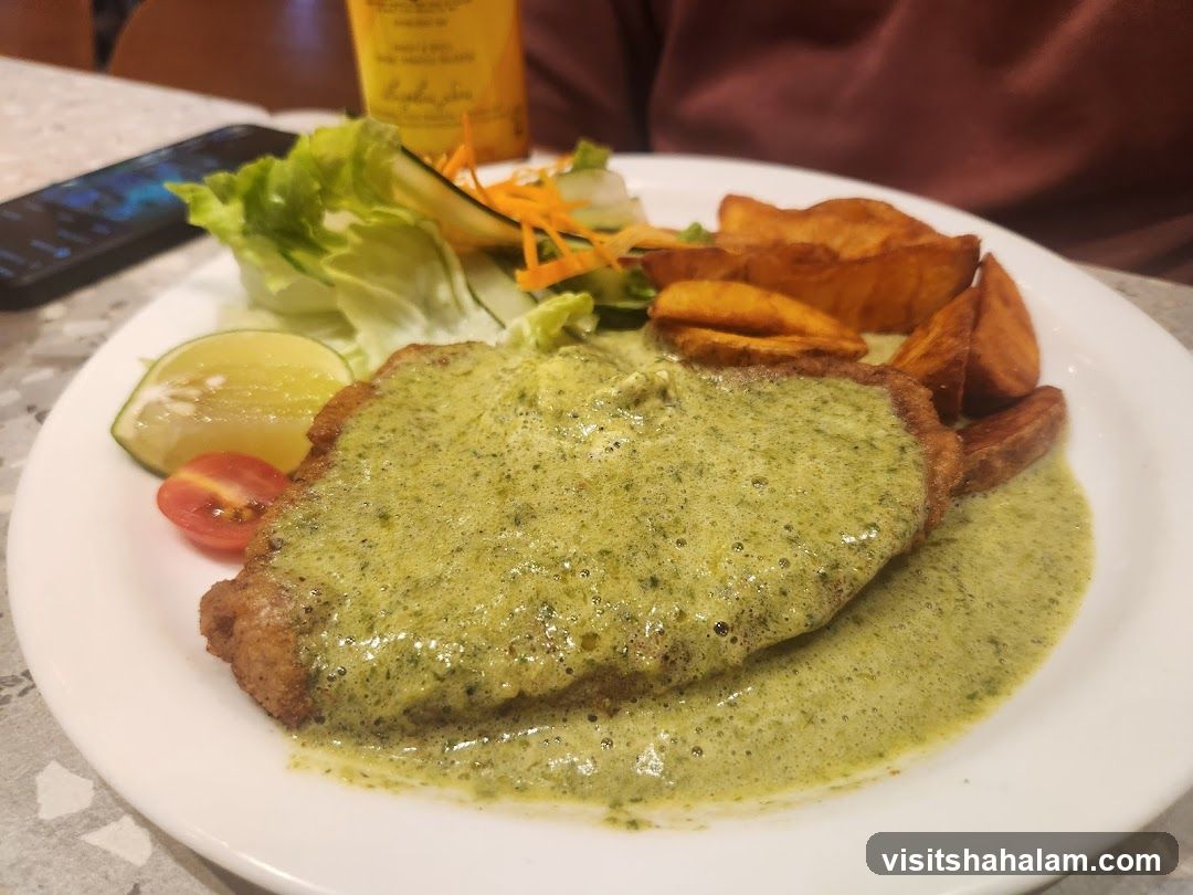 Breaded cutlet with green sauce and potato wedges