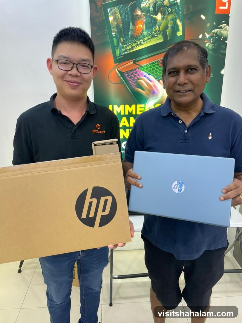 Two men holding a laptop and a box
