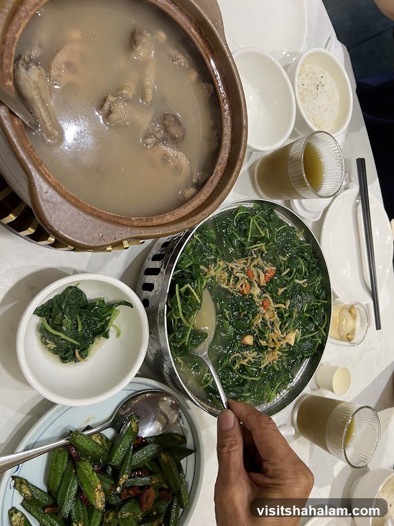 A table laden with various dishes, including a hearty soup, stir-fried vegetables, and okra.