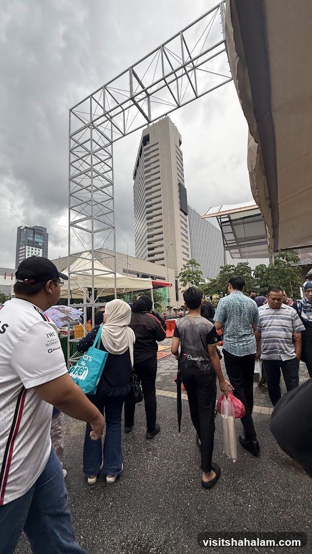 People walking under a metal structure with buildings in the background