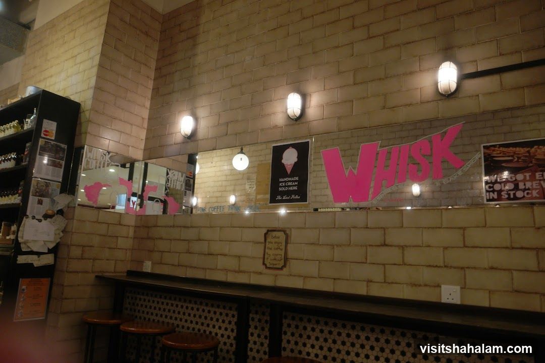 Interior of a cafe with tiled walls and a prominent "WHISK" logo.