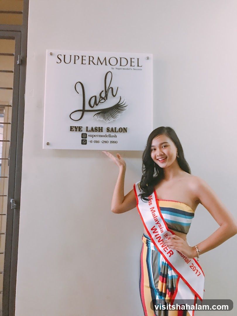 Woman with Miss Malaysia sash in front of lash salon sign