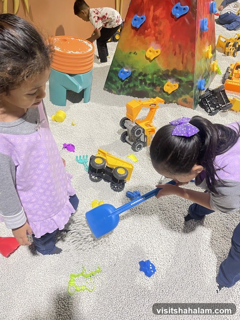 Children Playing in a Ball Pit with Toy Construction Vehicles