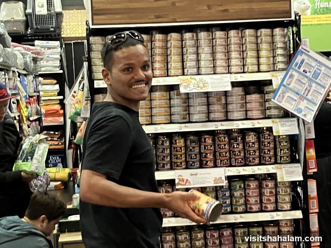 Man holding a can of cat food in a pet store