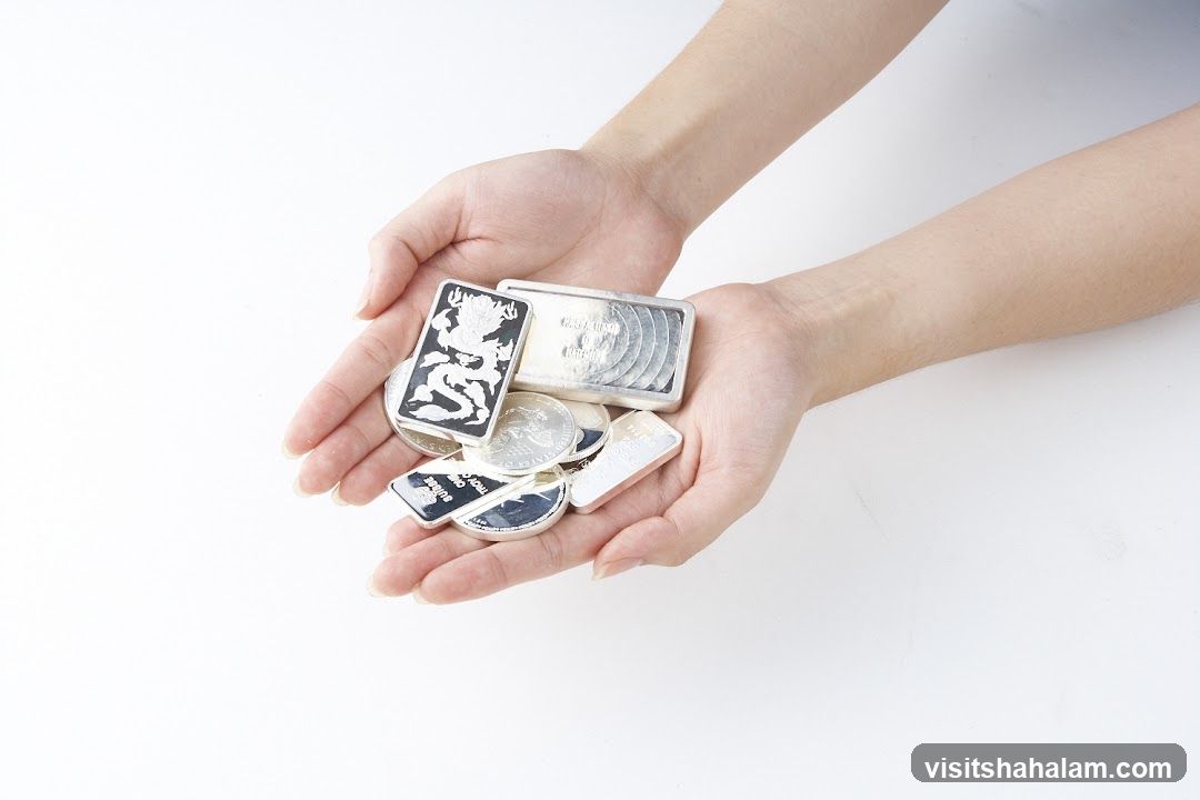 Hands holding silver bars and coins