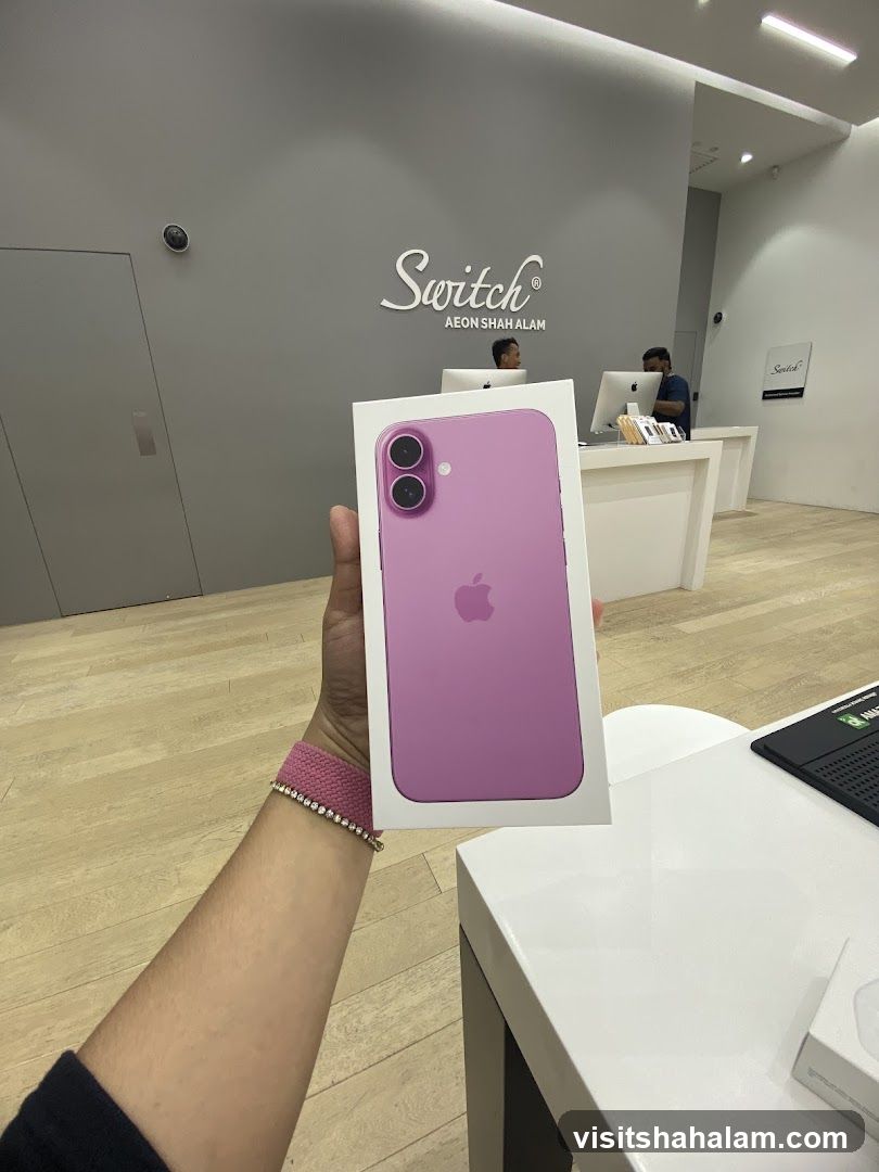 Person holding a pink iPhone box in a store