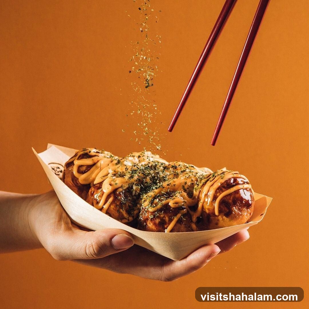 Takoyaki being sprinkled with herbs