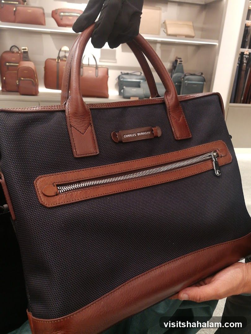 Hand holding a dark blue and brown leather trim briefcase