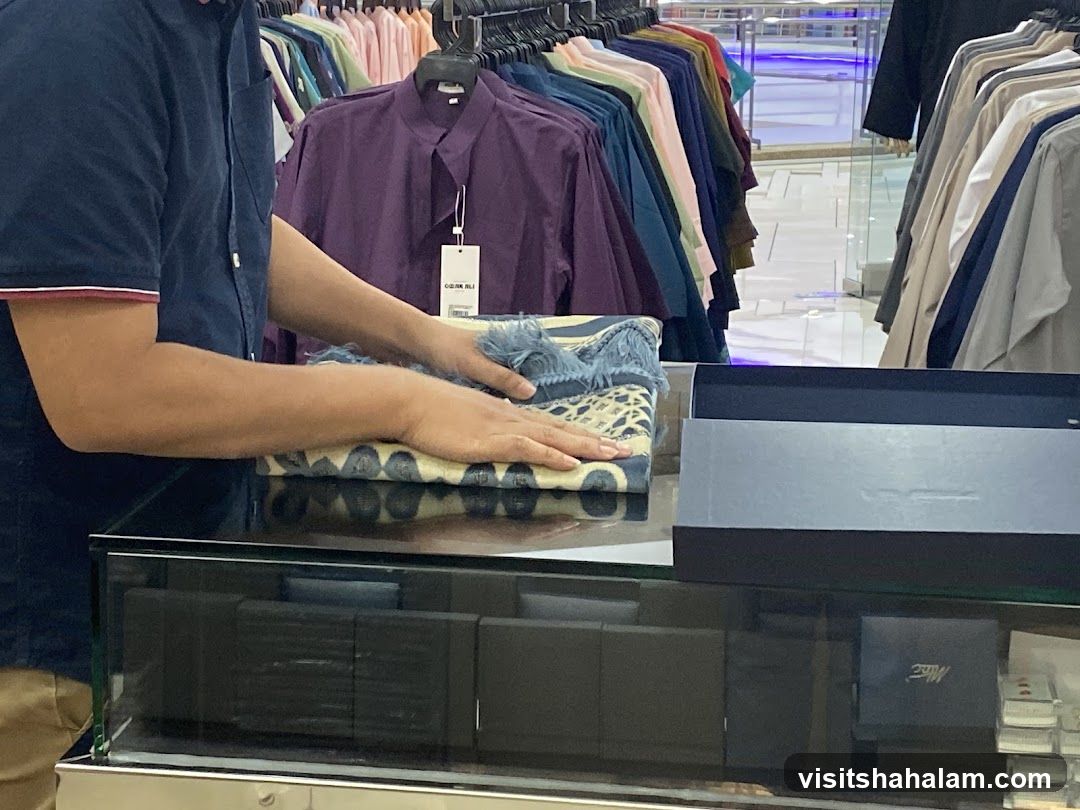 Man folding a patterned cloth in a store