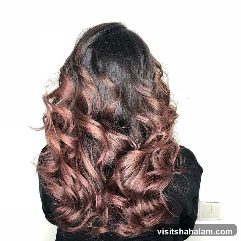 Woman with long, wavy, dark brown hair with rose gold highlights
