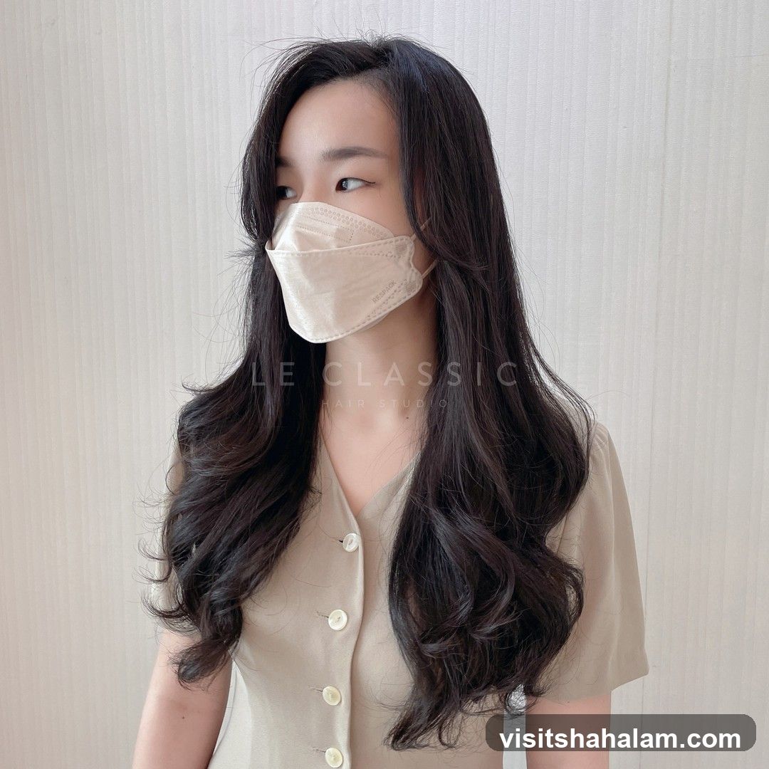 Woman with long, wavy dark hair and a beige mask