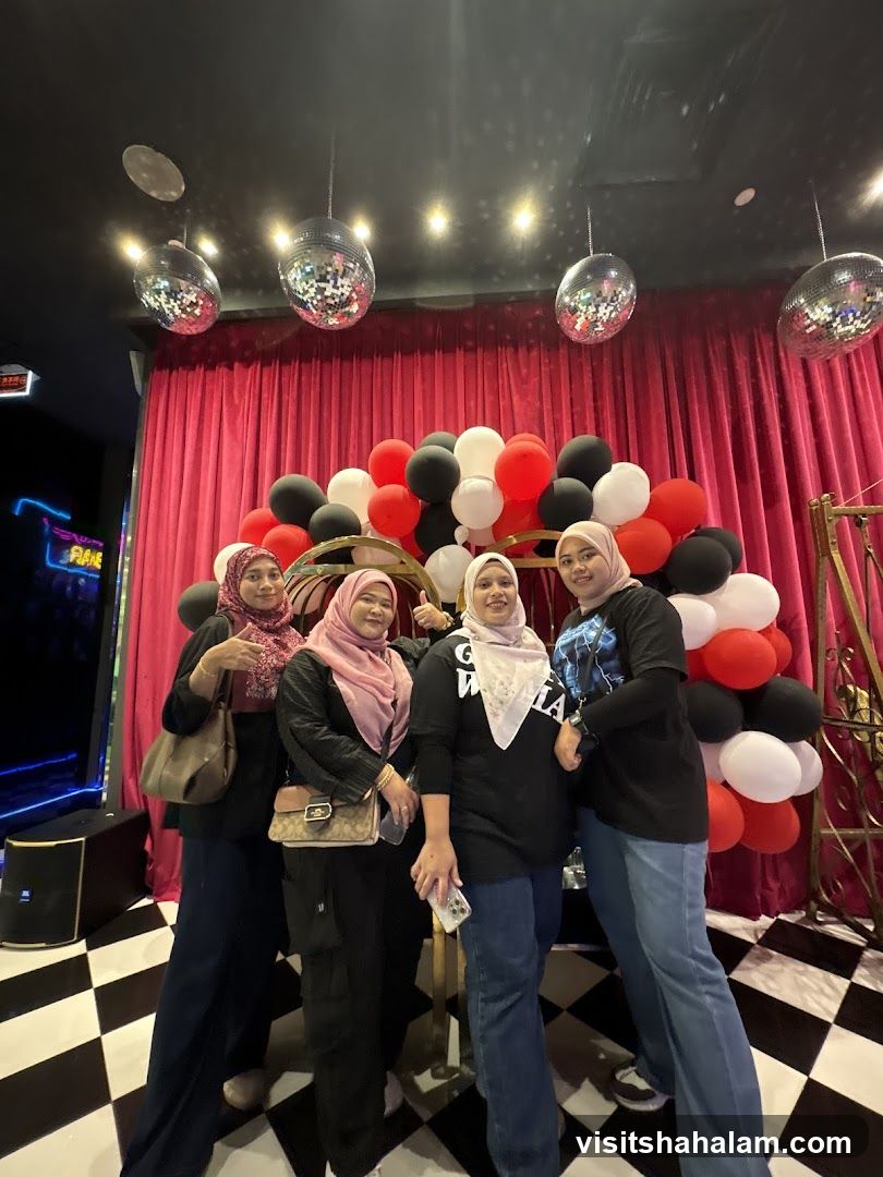 Four women posing in front of a balloon arch and red curtains
