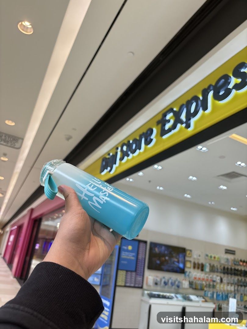 Hand holding a water bottle in front of a store
