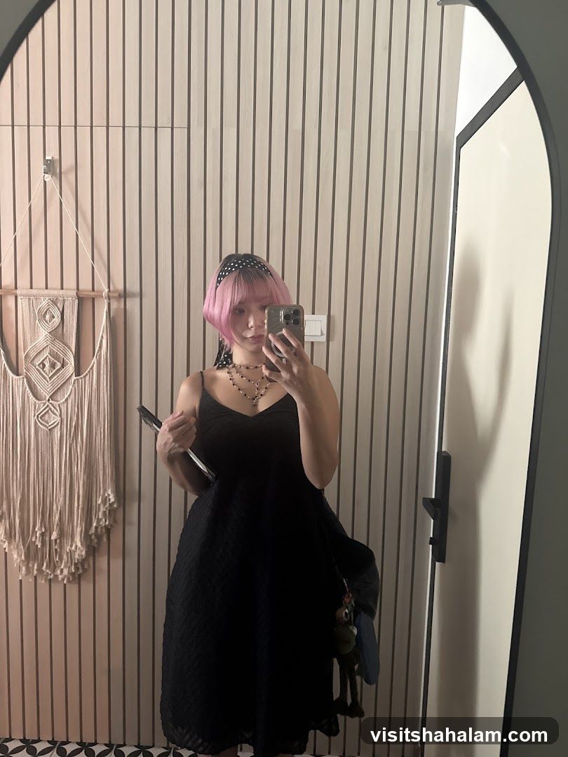 Woman in black dress taking a mirror selfie
