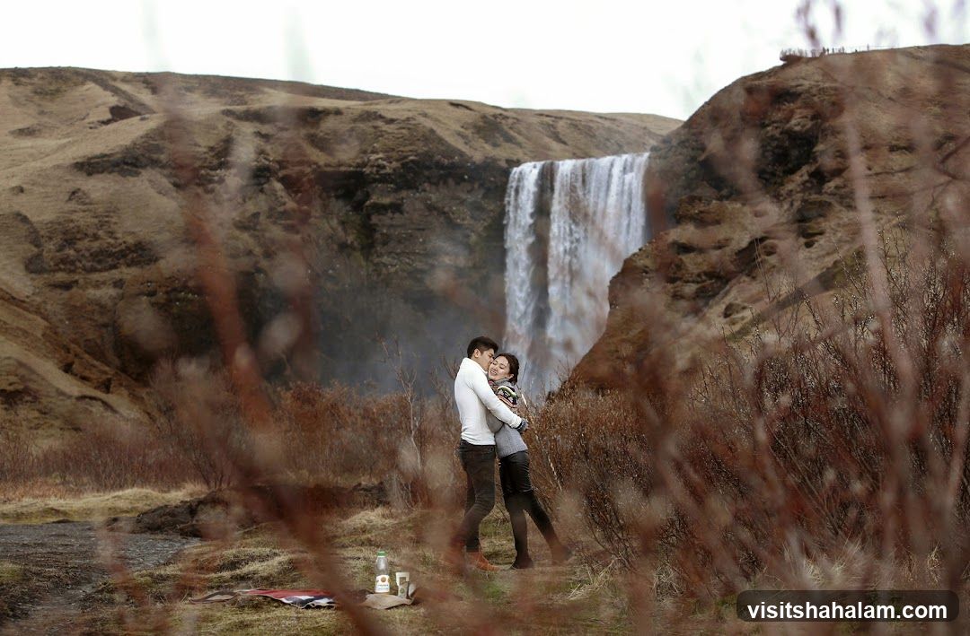 Couple embracing in front of a waterfall