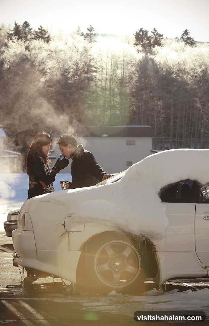 Couple sharing a drink by a snow-covered car