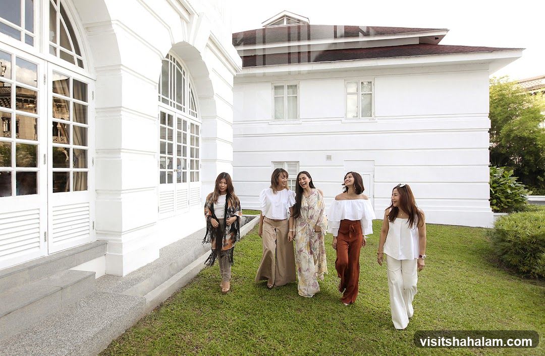 Five Women Walking on Grass in Front of White Building