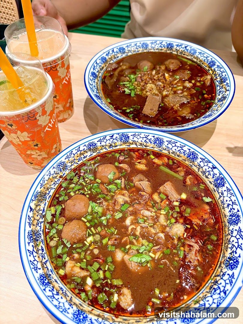 Two bowls of beef noodle soup and two drinks