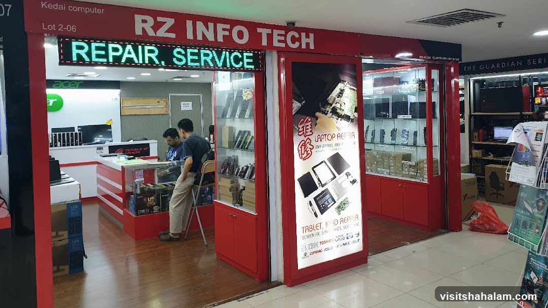 The exterior of a computer repair shop called RZ INFO TECH. A digital sign above the entrance reads "REPAIR, SERVICE". The shop has red accents and display cases filled with computer parts and accessories. A promotional poster for laptop and tablet repair is visible on the right side of the entrance.