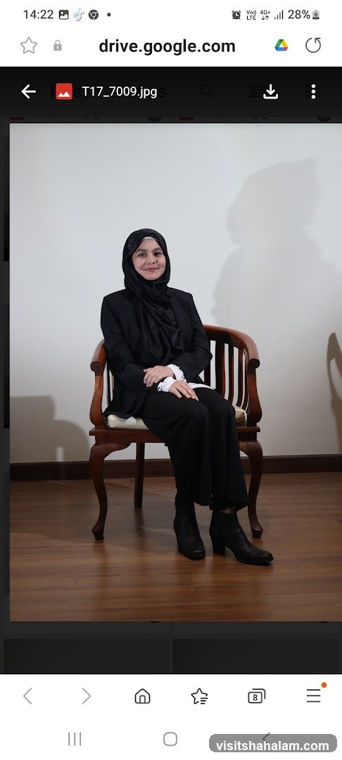 Woman in black suit and hijab sitting on a chair