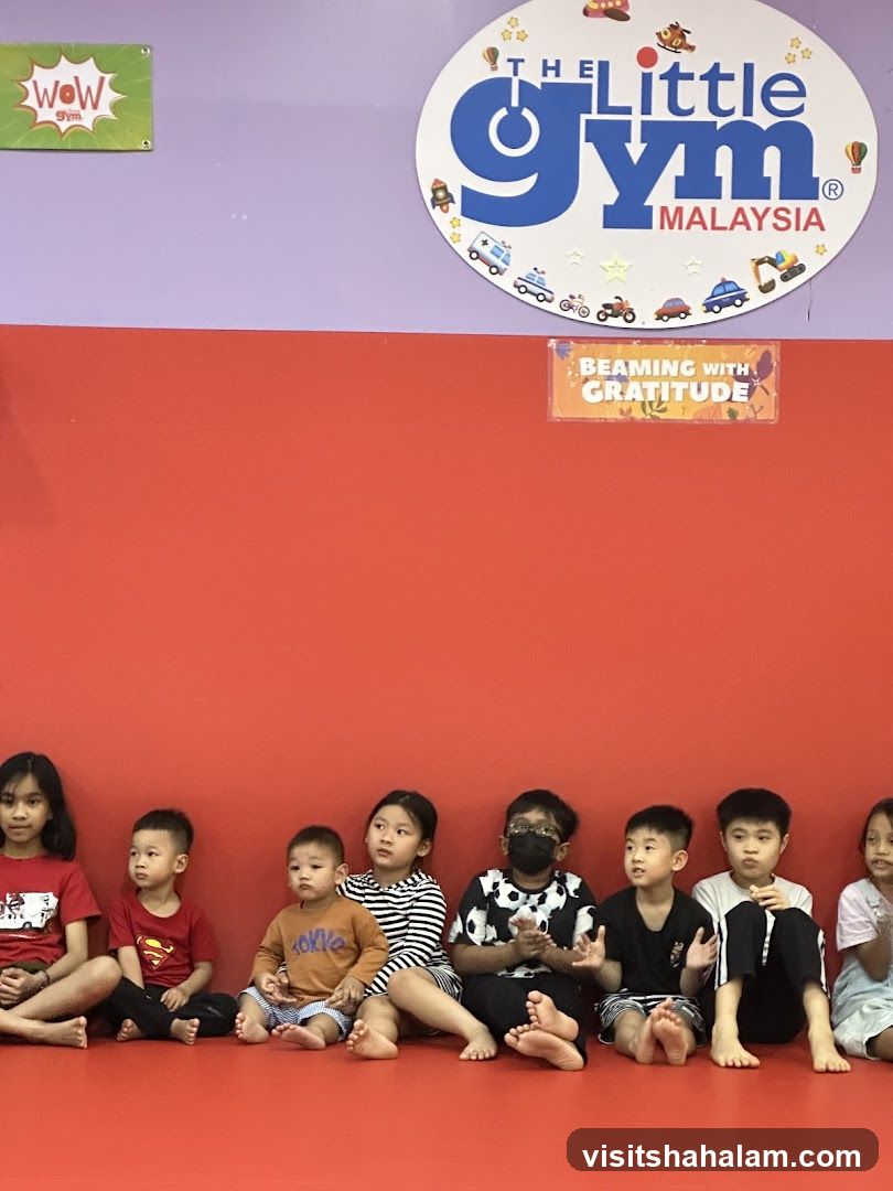 Children sitting in front of a wall with logos